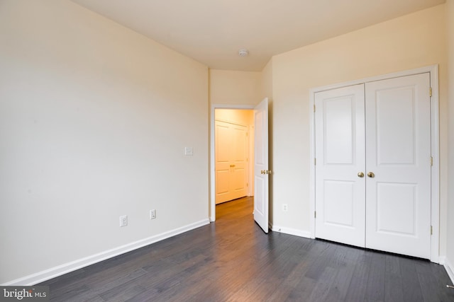 unfurnished bedroom with dark hardwood / wood-style flooring and a closet