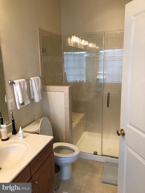 bathroom with vanity, toilet, tile patterned floors, and walk in shower