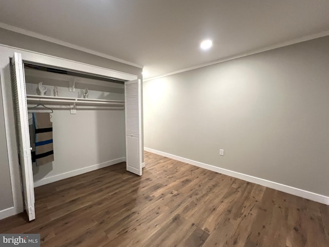 unfurnished bedroom with crown molding, dark hardwood / wood-style floors, and a closet