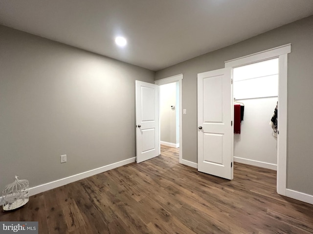 unfurnished bedroom featuring a walk in closet and dark hardwood / wood-style floors