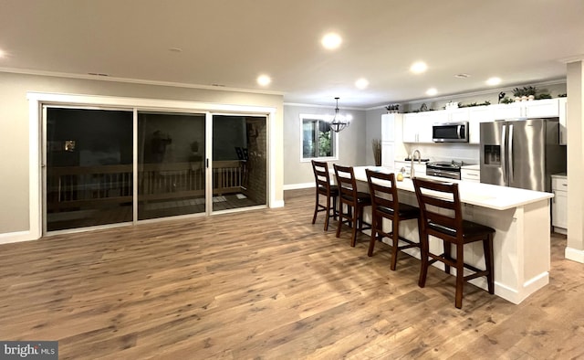 kitchen featuring stainless steel appliances, an island with sink, a breakfast bar area, and white cabinets