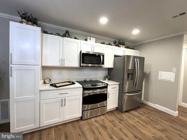 kitchen with white cabinetry, ornamental molding, stainless steel appliances, and dark wood-type flooring