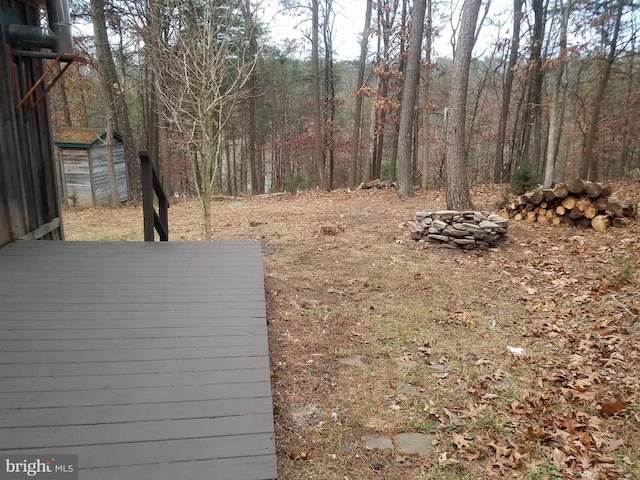 view of yard featuring an outbuilding, a deck, and an outdoor fire pit