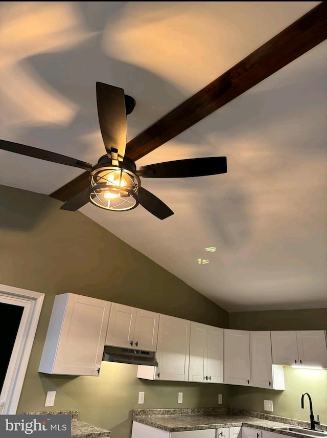 interior details featuring white cabinetry, sink, and dark stone counters