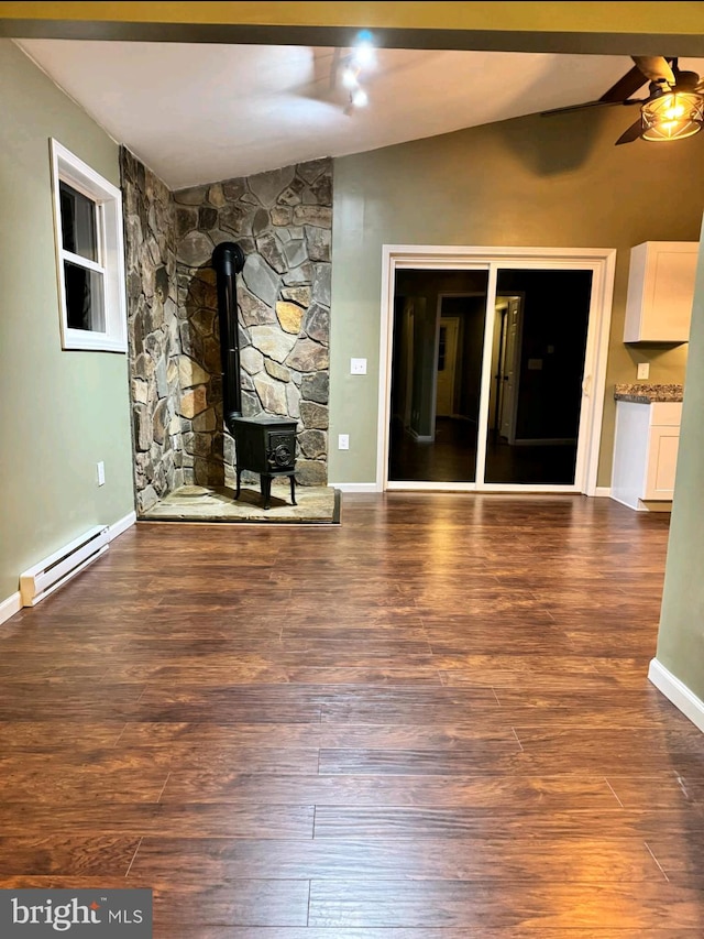 unfurnished living room with dark wood-type flooring, ceiling fan, baseboard heating, vaulted ceiling, and a wood stove