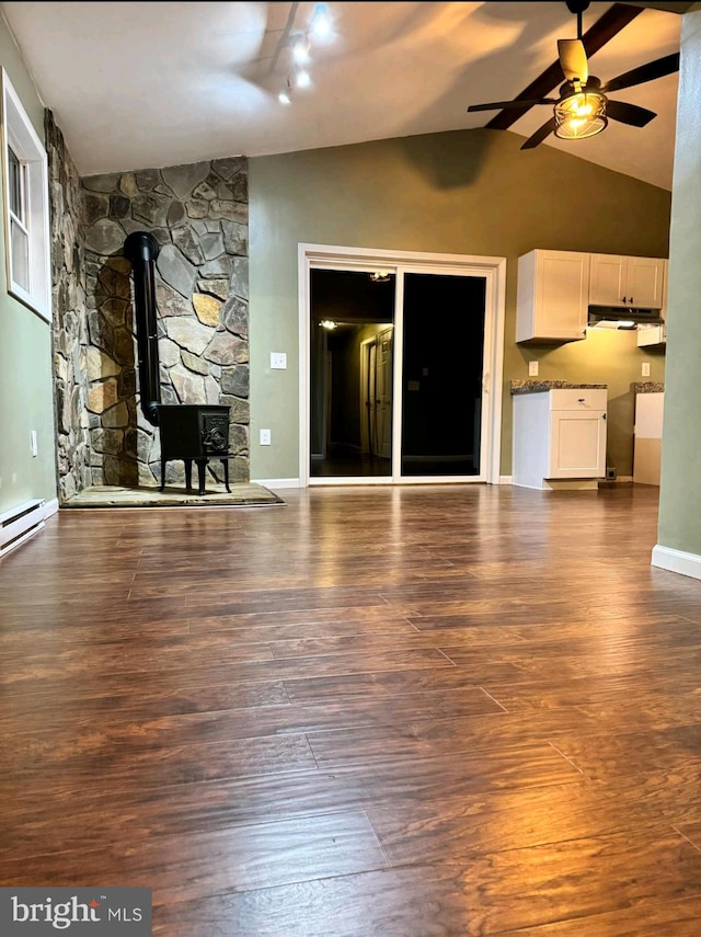 unfurnished living room featuring ceiling fan, a wood stove, vaulted ceiling with beams, and dark hardwood / wood-style flooring