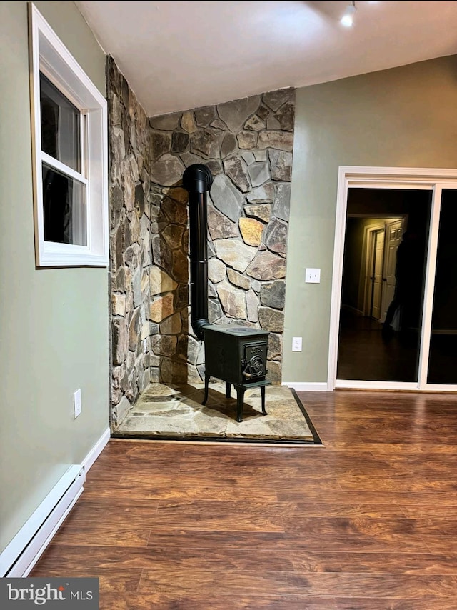 room details with wood-type flooring, a wood stove, and a baseboard heating unit