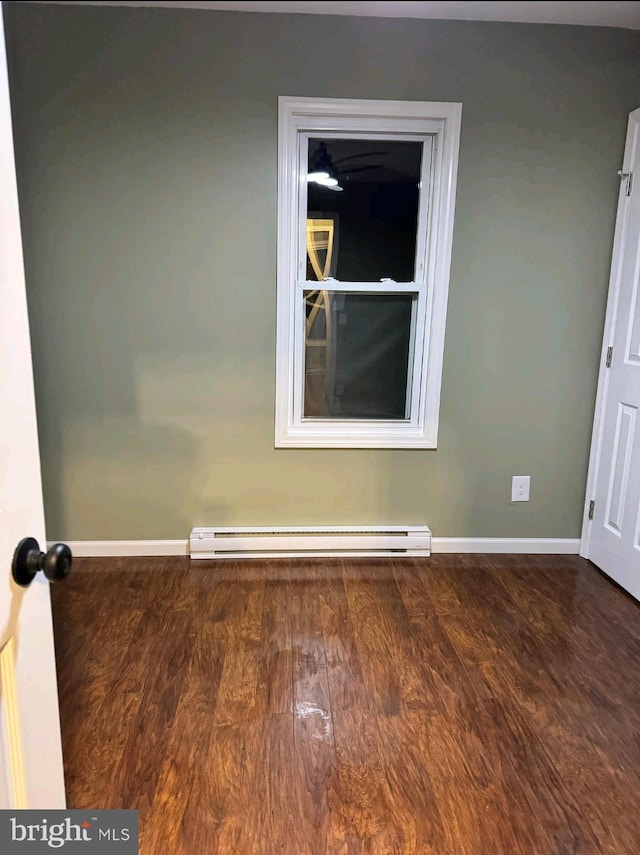 empty room featuring hardwood / wood-style flooring and baseboard heating