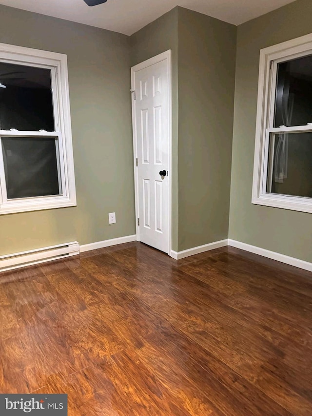 empty room featuring dark wood-type flooring and a baseboard radiator