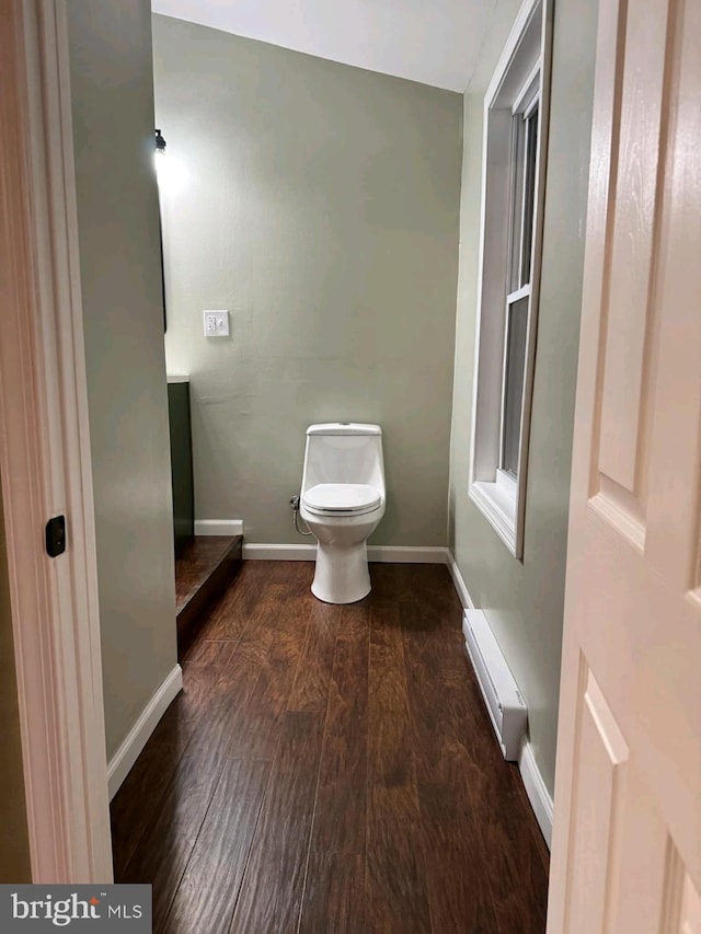 bathroom with toilet, hardwood / wood-style floors, and a baseboard heating unit