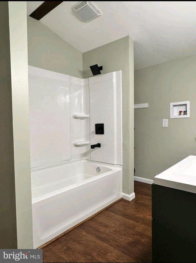 bathroom featuring hardwood / wood-style flooring, shower / bathtub combination, vanity, and vaulted ceiling