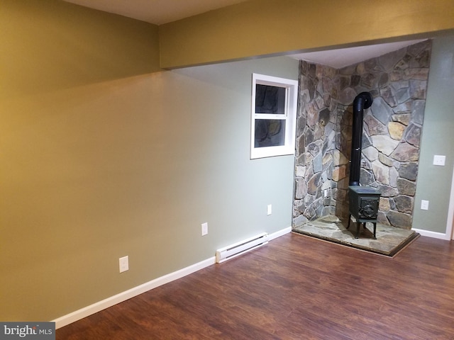 unfurnished living room with baseboard heating, a wood stove, and hardwood / wood-style flooring