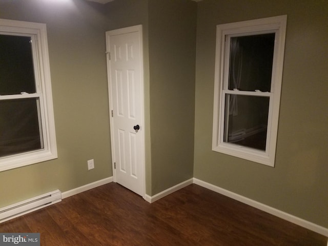 spare room featuring baseboard heating and dark hardwood / wood-style floors