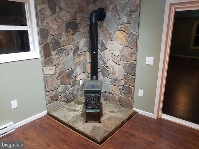 interior details featuring a baseboard heating unit, wood-type flooring, and a wood stove