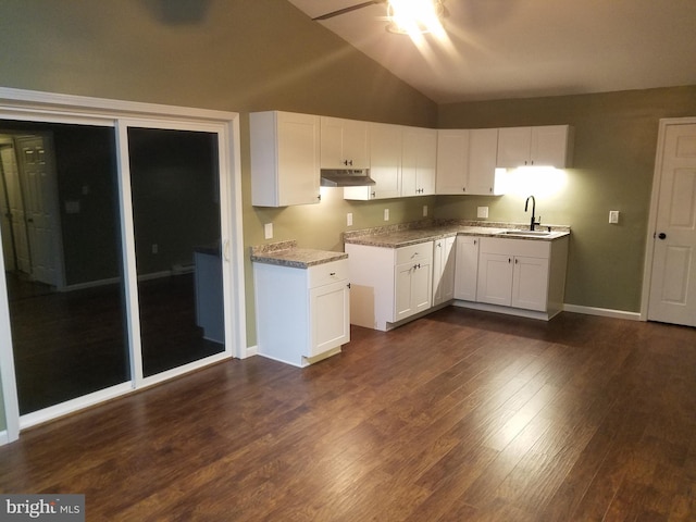 kitchen featuring sink, white cabinetry, dark hardwood / wood-style floors, light stone countertops, and vaulted ceiling