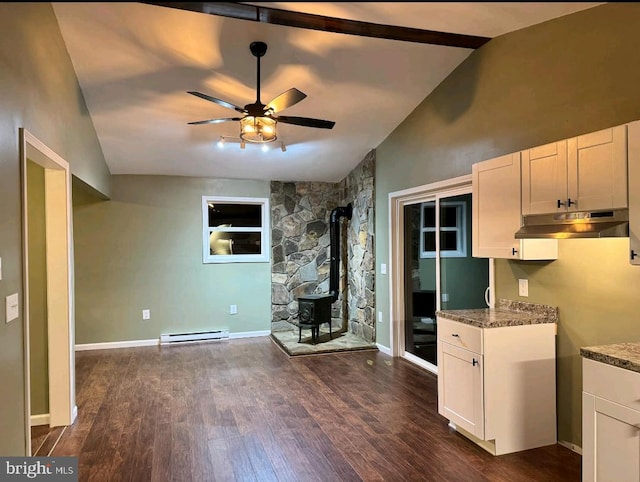 kitchen featuring dark wood-type flooring, white cabinetry, a wood stove, baseboard heating, and dark stone counters