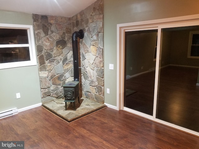 room details with hardwood / wood-style flooring, a baseboard radiator, and a wood stove