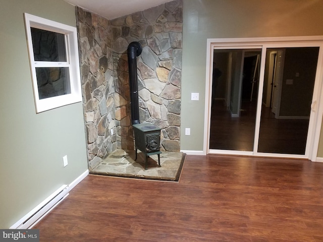 unfurnished living room featuring a baseboard heating unit, hardwood / wood-style floors, and a wood stove