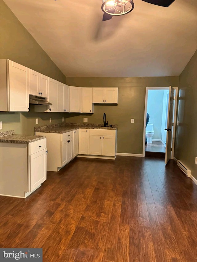 kitchen with vaulted ceiling, dark hardwood / wood-style floors, white cabinetry, dark stone countertops, and a baseboard heating unit