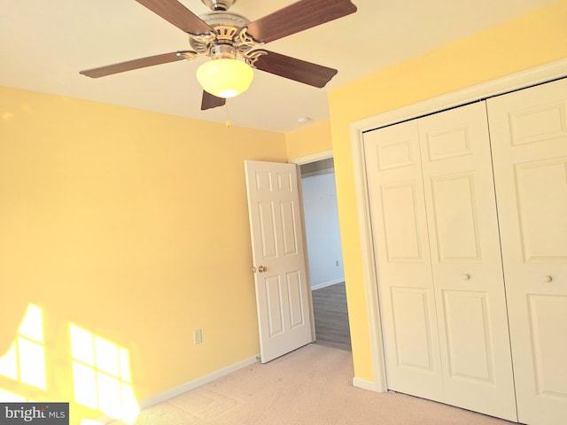 unfurnished bedroom featuring ceiling fan, a closet, and light carpet