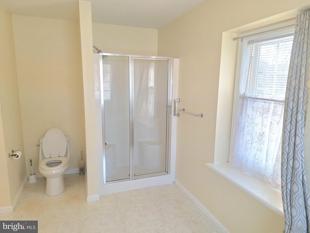 bathroom featuring toilet and a shower with shower door