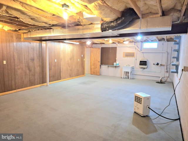 basement featuring sink, heating unit, and wood walls