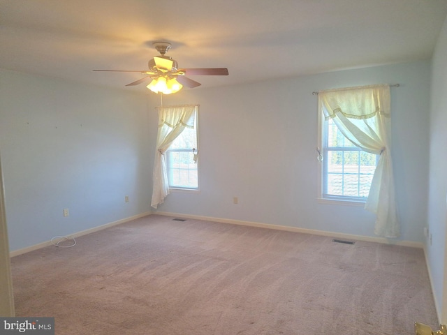 spare room with ceiling fan, light colored carpet, and plenty of natural light