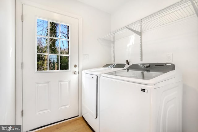 laundry room with washing machine and clothes dryer and light wood-type flooring