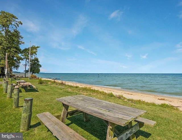 view of community featuring a water view, a yard, and a beach view