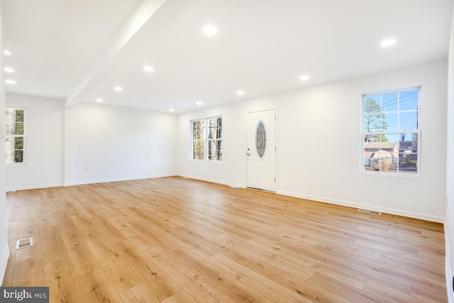 unfurnished living room with light hardwood / wood-style floors and beamed ceiling