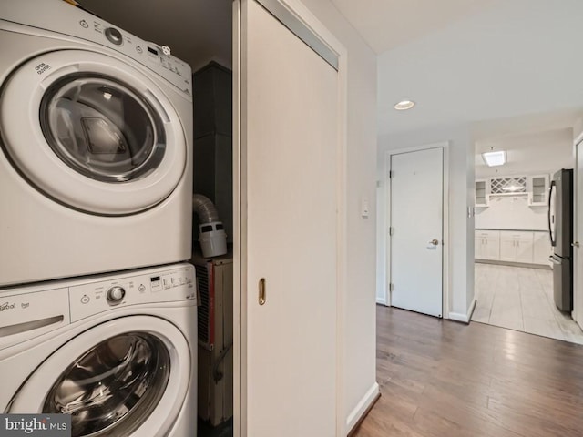 clothes washing area with stacked washer / drying machine and light hardwood / wood-style flooring