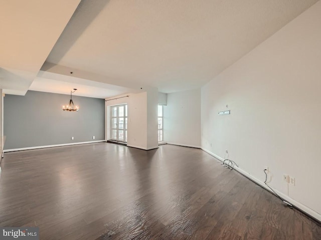 spare room featuring dark hardwood / wood-style flooring and a chandelier