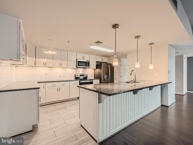 kitchen with stainless steel appliances, a kitchen bar, sink, and white cabinets