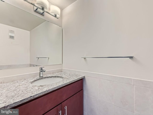 bathroom featuring vanity and tile walls