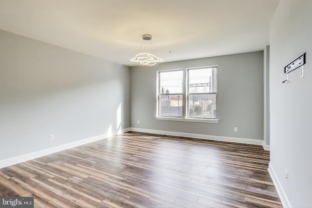 unfurnished room with a chandelier and dark hardwood / wood-style flooring