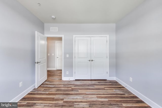 unfurnished bedroom featuring dark hardwood / wood-style flooring and a closet