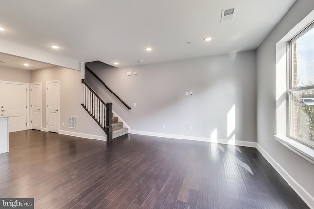 unfurnished living room featuring dark wood-type flooring and a wealth of natural light