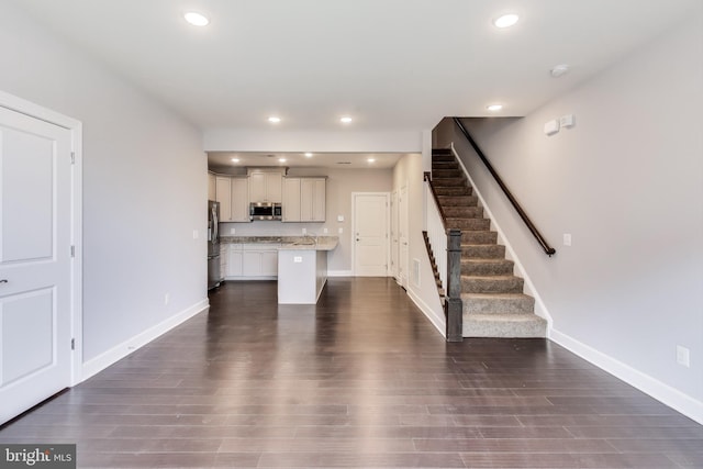 kitchen featuring dark hardwood / wood-style flooring, white cabinetry, a center island, and appliances with stainless steel finishes