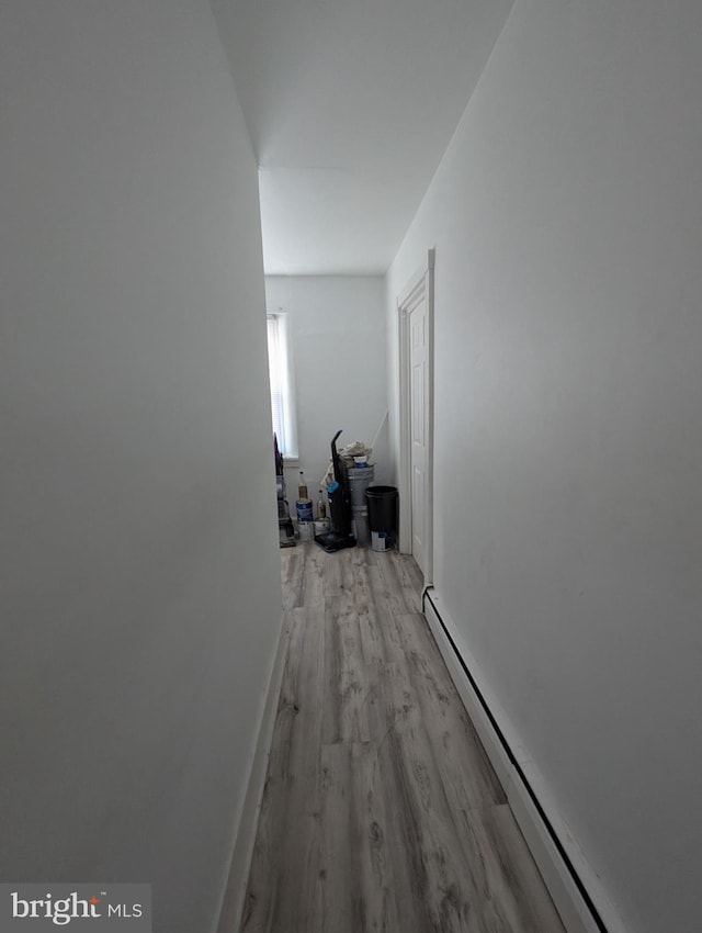 corridor featuring baseboard heating and light hardwood / wood-style flooring