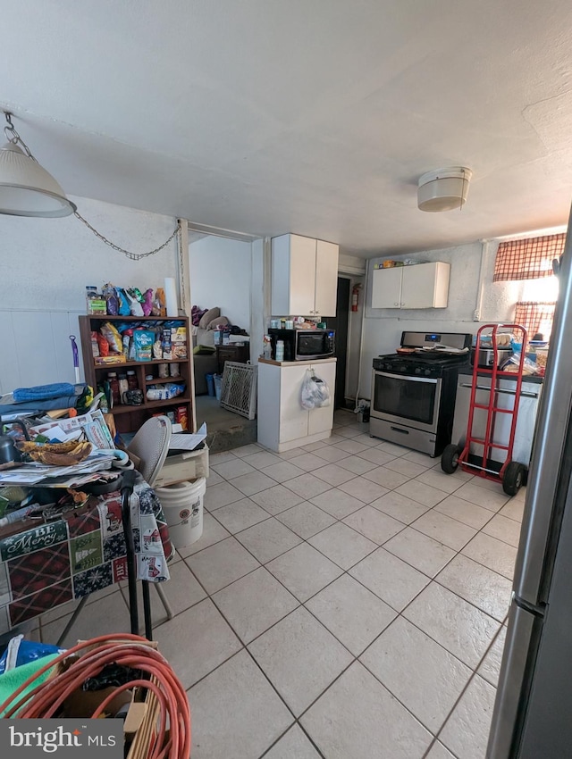 kitchen with white cabinetry, light tile patterned floors, and stainless steel gas range oven