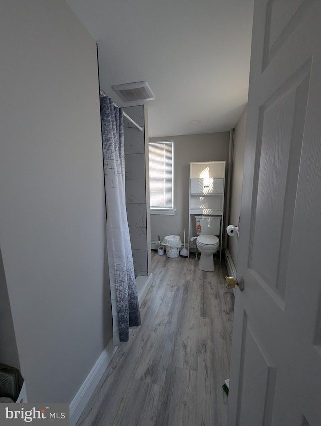 bathroom featuring toilet, wood-type flooring, and a shower with shower curtain