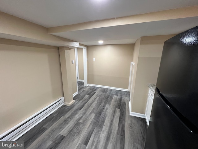 basement featuring a baseboard radiator, fridge, and dark hardwood / wood-style floors