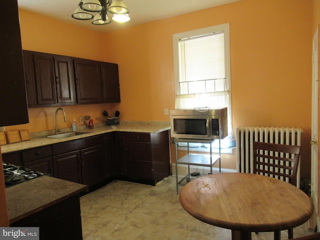 kitchen featuring radiator, sink, an inviting chandelier, dark brown cabinetry, and gas stovetop