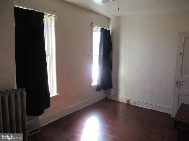 spare room featuring ceiling fan, radiator, and dark hardwood / wood-style flooring