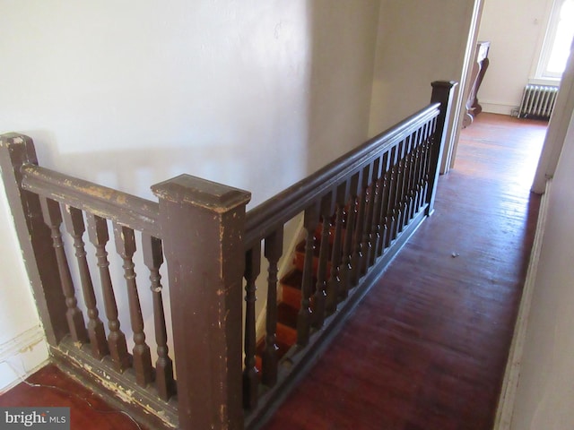 stairs featuring hardwood / wood-style floors and radiator heating unit