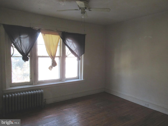 spare room with radiator, dark wood-type flooring, and ceiling fan