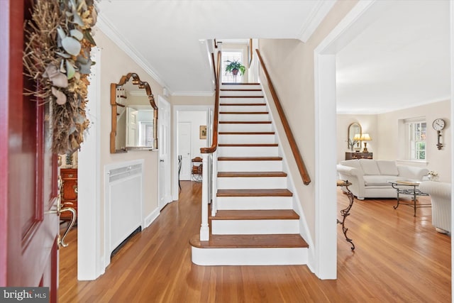 stairs featuring crown molding, wood-type flooring, and a wealth of natural light