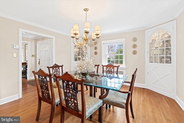 dining space featuring an inviting chandelier, ornamental molding, and light hardwood / wood-style floors