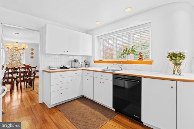 kitchen featuring light hardwood / wood-style flooring, black dishwasher, hanging light fixtures, and white cabinets