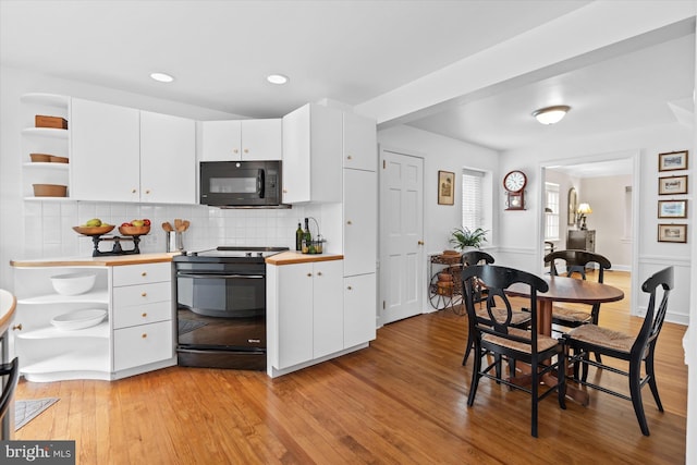 kitchen with white cabinetry, decorative backsplash, light hardwood / wood-style floors, and black appliances